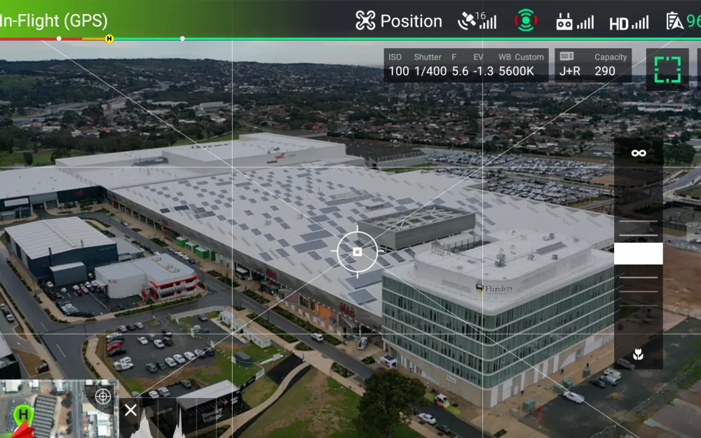 A drone controller mid-flight, showing a live aerial view of a commercial site